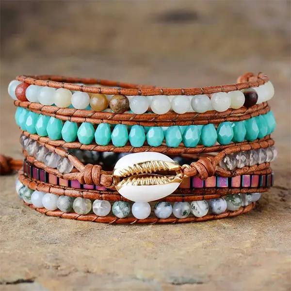 Bracelet Boho (Wrap) Coquillage Cauris posé sur un sol en pierre vue de face kaosix