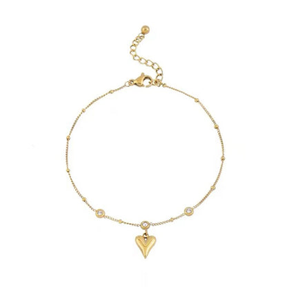 Bracelet de cheville en acier inoxydable doré pendentif cœur et zircons cubiques sur un sol blanc Kaosix