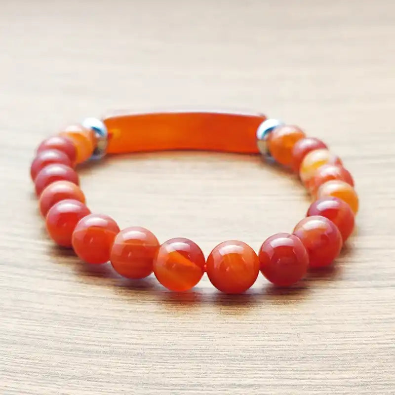 Bracelet en Agate Rouge Bande Courbe et Perles posé à plat sur une surface en bois vue de derrière Kaosix