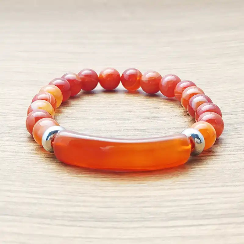 Bracelet en Agate Rouge Bande Courbe et Perles posé à plat sur une surface en bois vue de face Kaosix