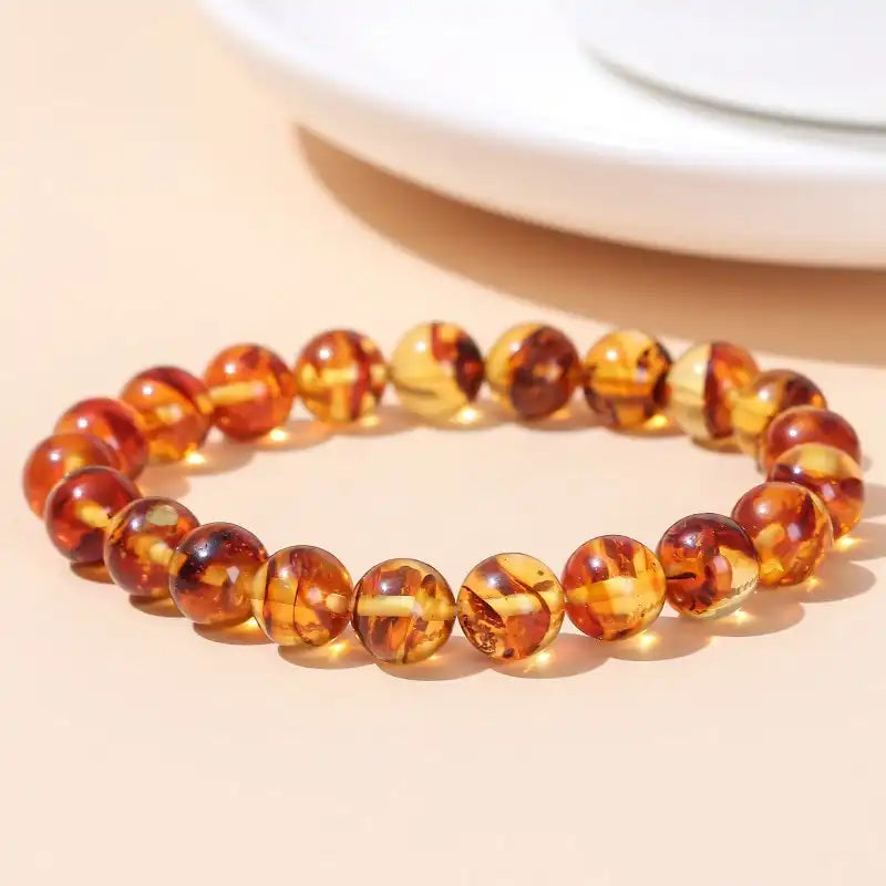 Bracelet en Perles d’Ambre Jaune posé sur une table couleur saumon à coté d'une assiette blanche Kaosix