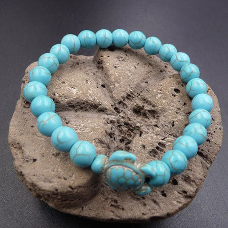 Bracelet pierre bleu turquoise tortue marine sur un rocher posé sur une table grise Kaosix