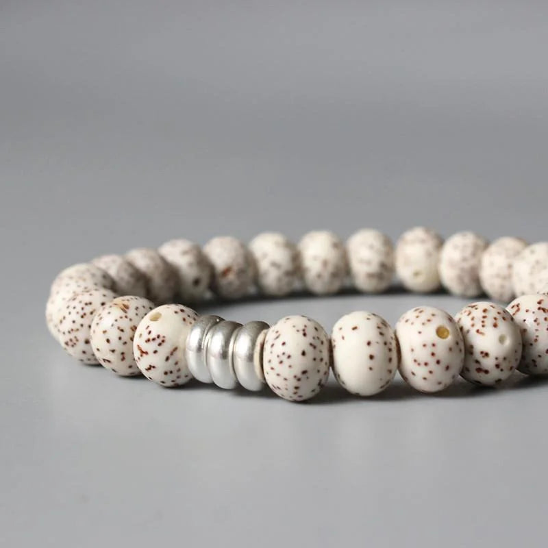 Bracelet tibétain graine de bodhi protection avec gros plan sur les anneaux métalliques et posé sur un sol gris Kaosix