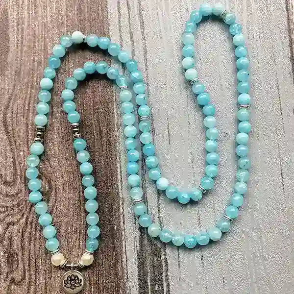 Mala 108 perles Aigue Marine Lotus déroulé sur un sol en bois kaosix