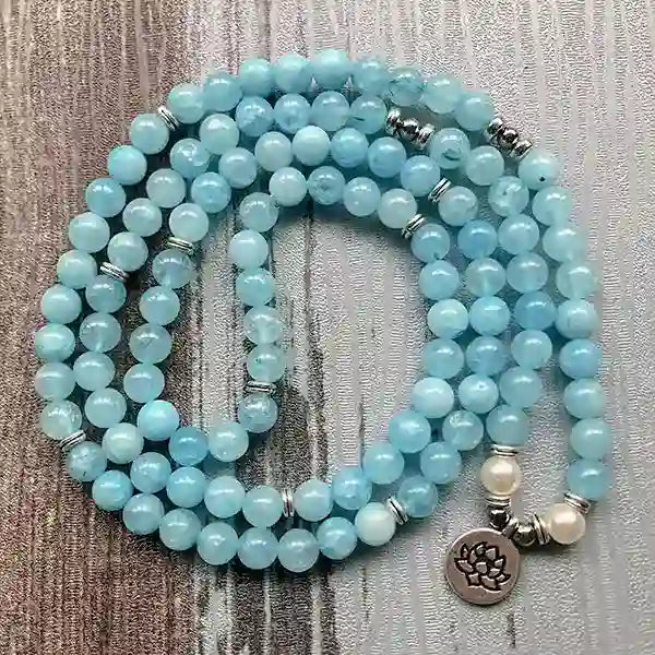 Mala 108 perles Aigue Marine Lotus enroulé à plat en serpent sur un sol en bois kaosix