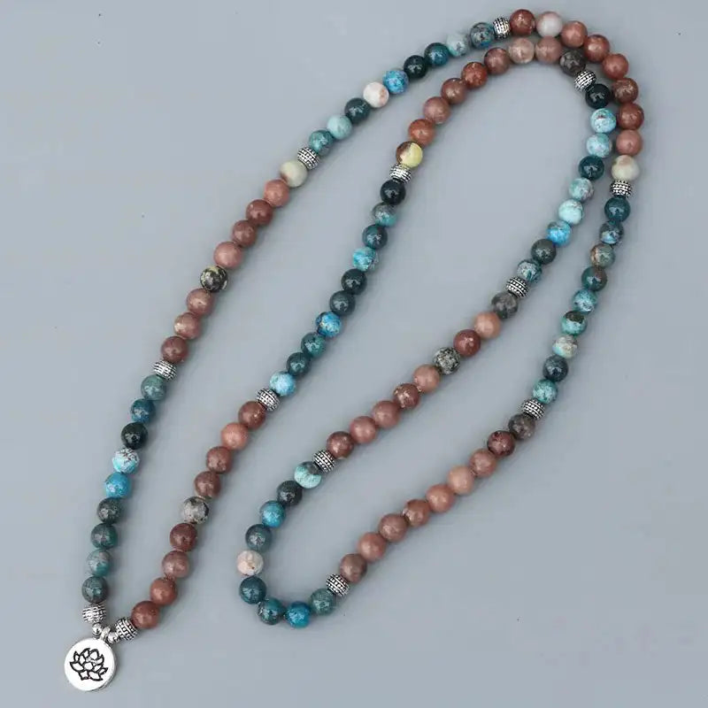 Mala 108 perles Apatite Pierre de Soleil Lotus déroulé sur un sol gris kaosix