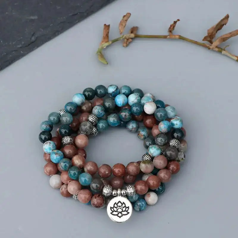 Mala 108 perles Apatite Pierre de Soleil Lotus sur un sol gris vue de dessus kaosix