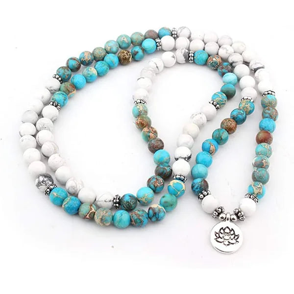 Mala 108 perles Howlite Turquoise Lotus déroulé sur un sol blanc kaosix