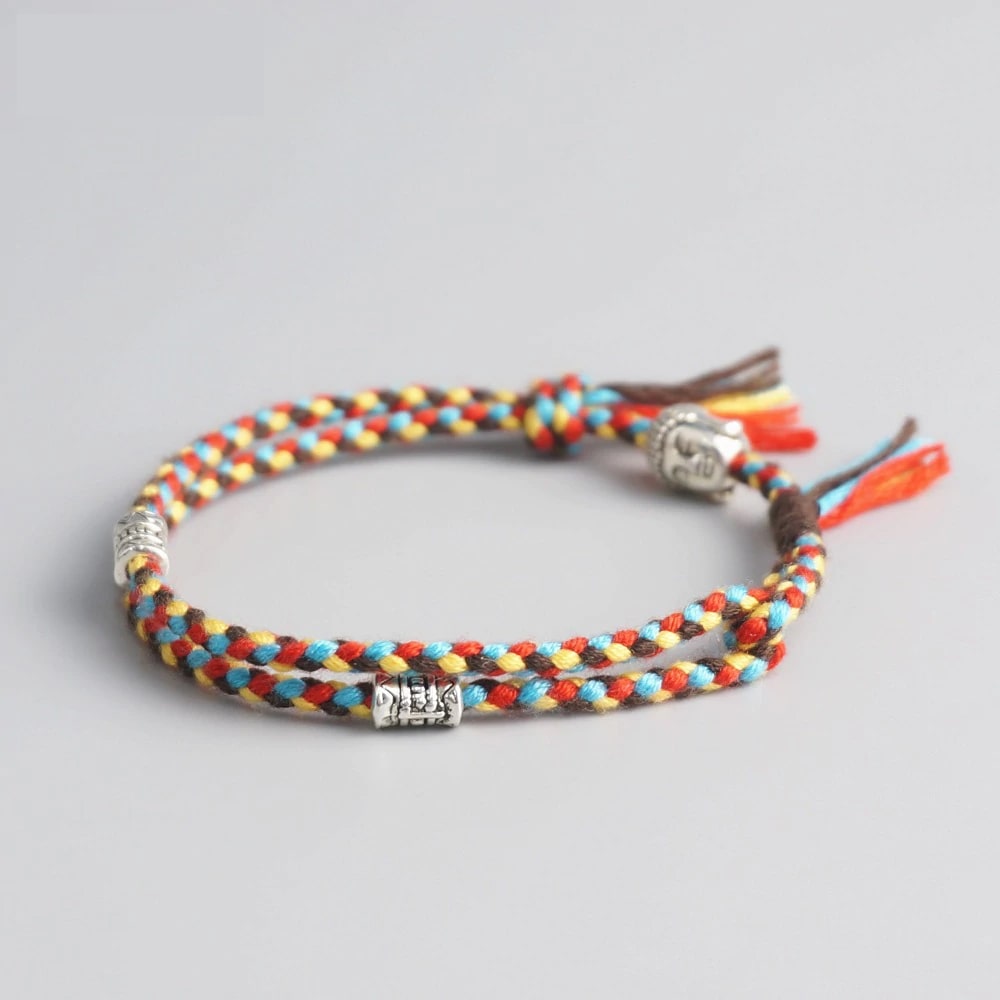 Bracelet Bouddha porte bonheur jaune et rouge tête de bouddha moulin à prières sur fond gris 2 Kaosix
