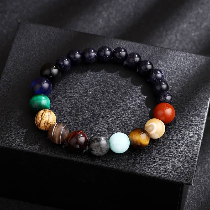 Bracelet Système Solaire avec 11 Planètes en Perles de Pierres posé sur une boite noire Kaosix