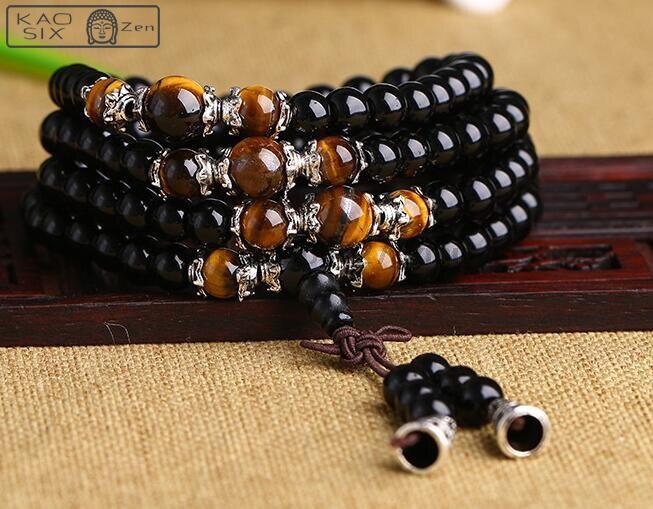 bracelet mala 108 perles onyx noir œil de tigre posé sur une planchette en bois rouge