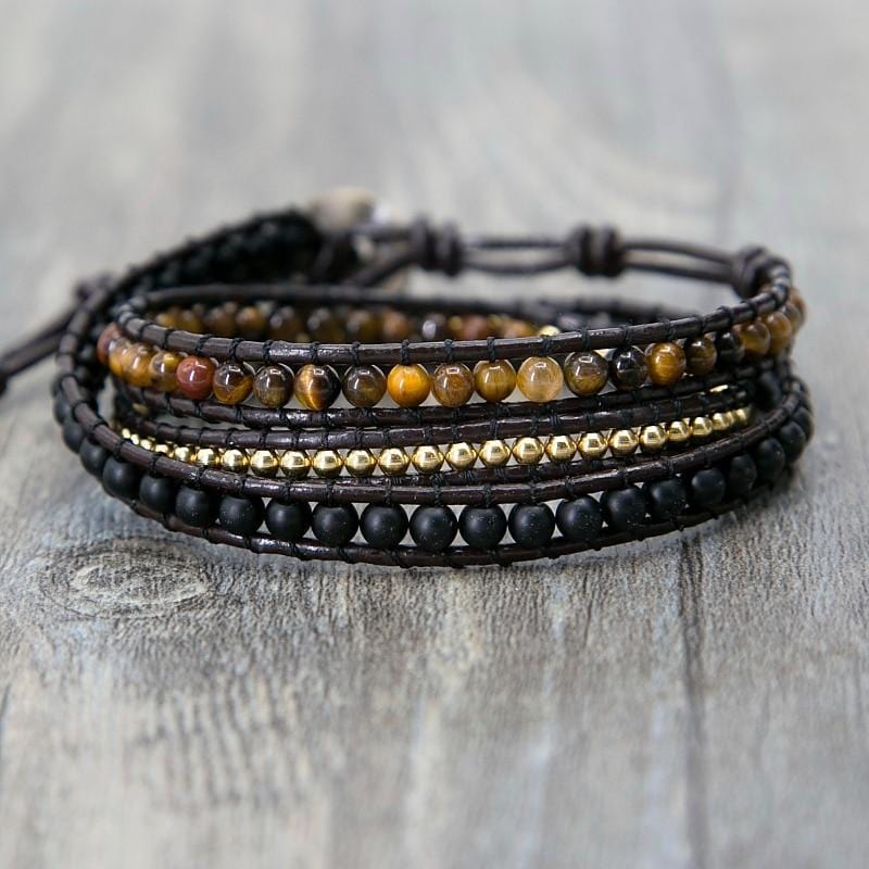 Bracelet wrap confiance en soi en œil de tigre et onyx noir posé sur plancher en bois gris kaosix