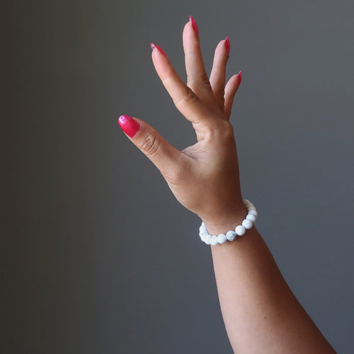 Bracelet en howlite calme boule 8 mm sur un poignet de femme avec le bras levé Kaosix