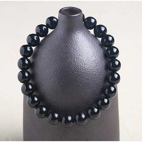 Bracelet en tourmaline noire ancrage boule 8 mm posé sur un vase gris Kaosix