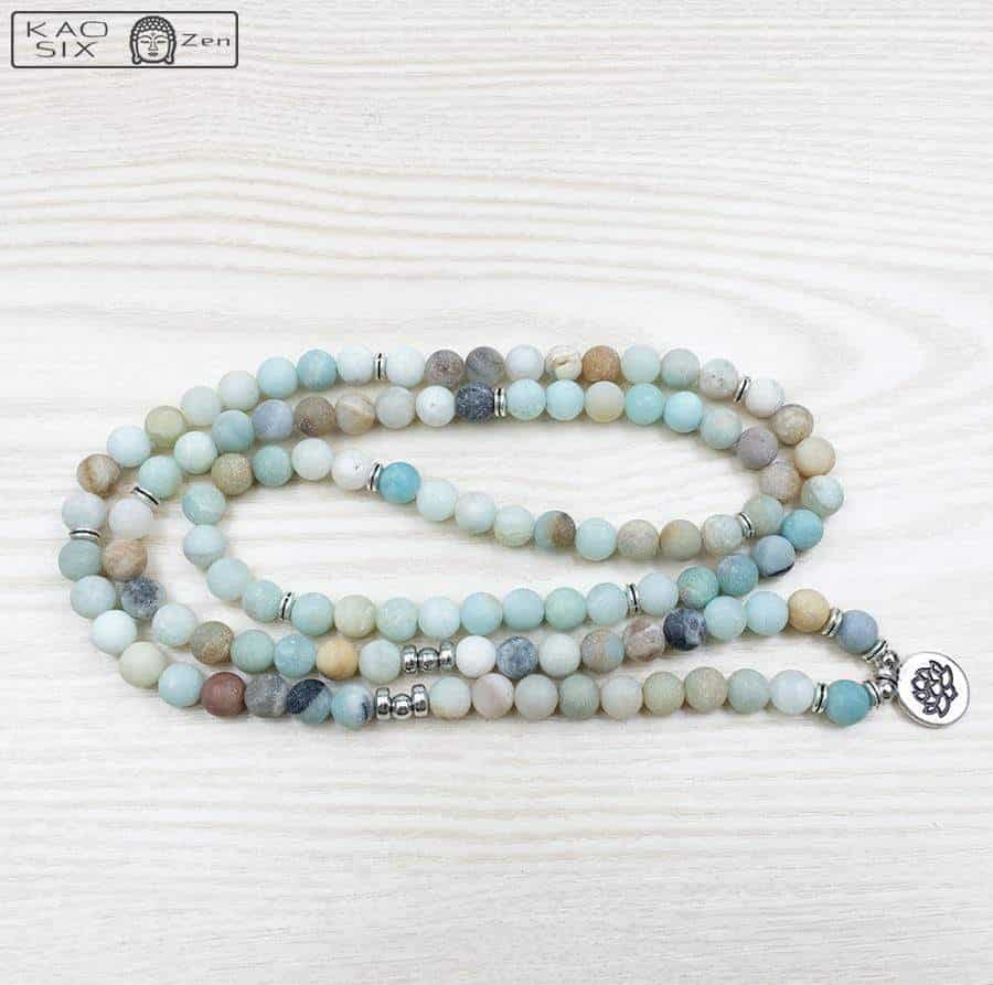 Bracelet mala 108 perles amazonite lotus déroulé sur plancher en bois clair Kaosix