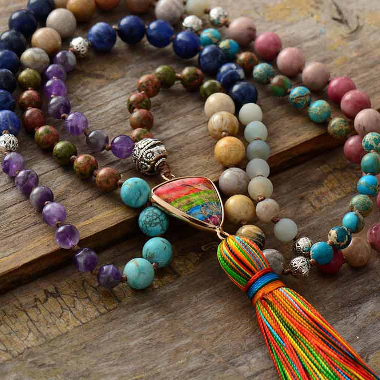 Bracelet mala 108 perles jaspe turquoise améthyste rhodonite à plat sur une surface en bois et vue en gros plan du pompon et du triangle Kaosix