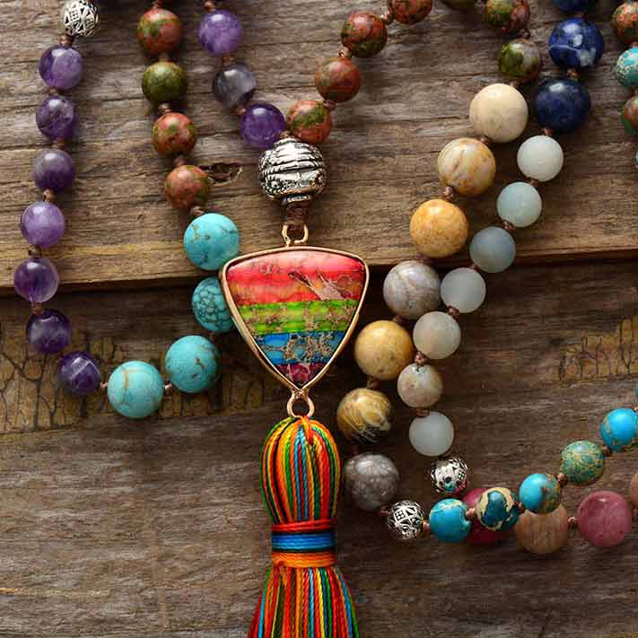 Bracelet mala 108 perles jaspe turquoise améthyste rhodonite sur une surface en bois et vue en gros plan du pompon et du triangle Kaosix