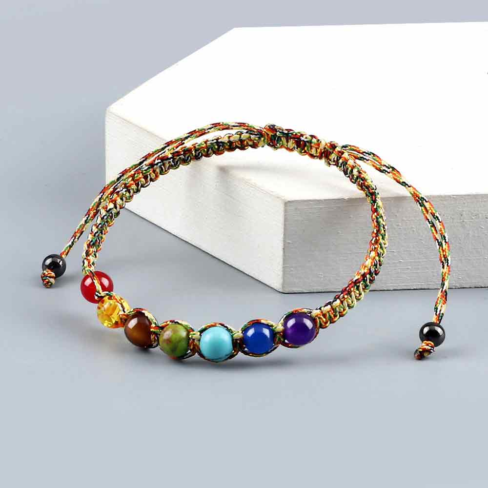Bracelet tibétain 7 chakras macramé posé sur un socle en bois blanc Kaosix