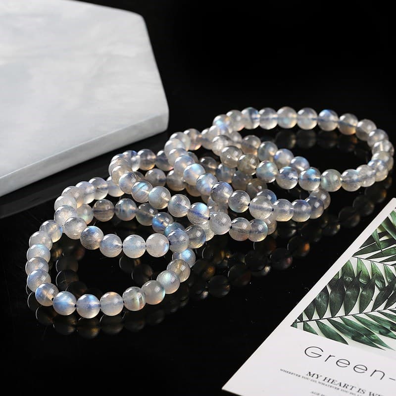 Cinq bracelets en labradorite blanche sur une table noire Kaosix