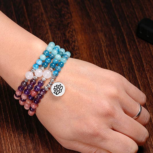 Mala 108 perles Rhodochrosite Apatite Améthyste Pierre de Soleil au poignet d'une femme et en gros plan Kaosix