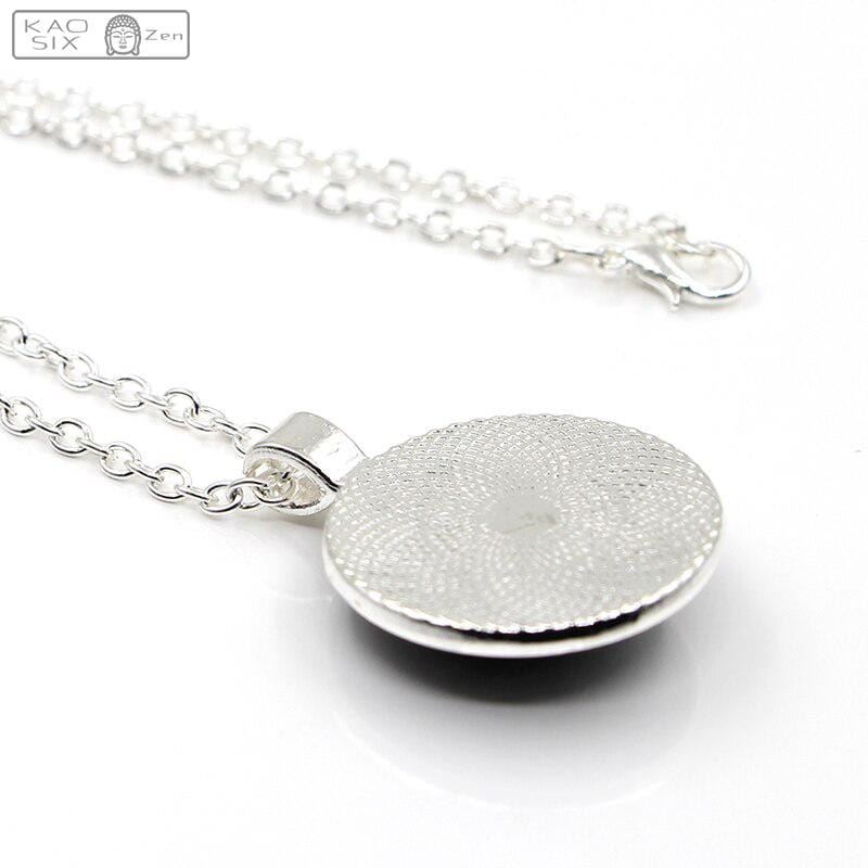 Pendentif Sri Yantra en verre à géométrie sacrée posé face contre terre sur fond blanc kaosix