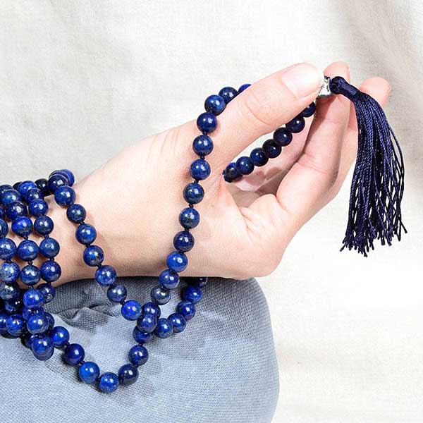 Une femme tien le Mala 108 perles Lapis Lazuli et symbole arbre de vie dans sa main Kaosix