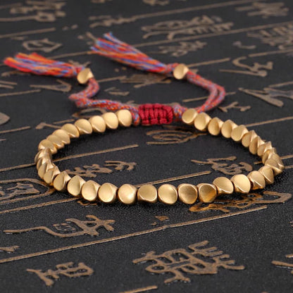 bracelet tibétain en perles de cuivre sur tapis noir avec caractères chinois dorés Kaosix