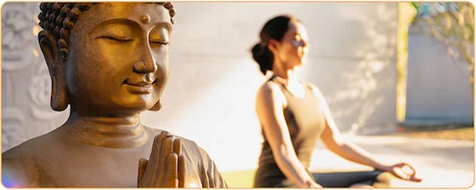 Tête de Bouddha en prière en avant plan et femme en position de lotus en arrière plan et floue Kaosix