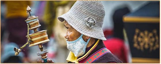 Un vieux tibétain qui tient un moulin à prières dans sa main Kaosix