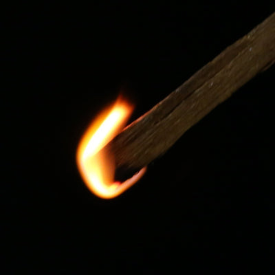 Batônnet de Bois de santal à brûler en incandescence sur un fond noir Kaosix