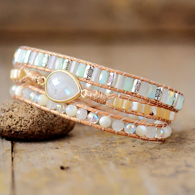 Bracelet Boho (wrap) Pierre de Lune Intuition posé à cheval sur une pierre et sur un plancher en bois vue de face kaosix