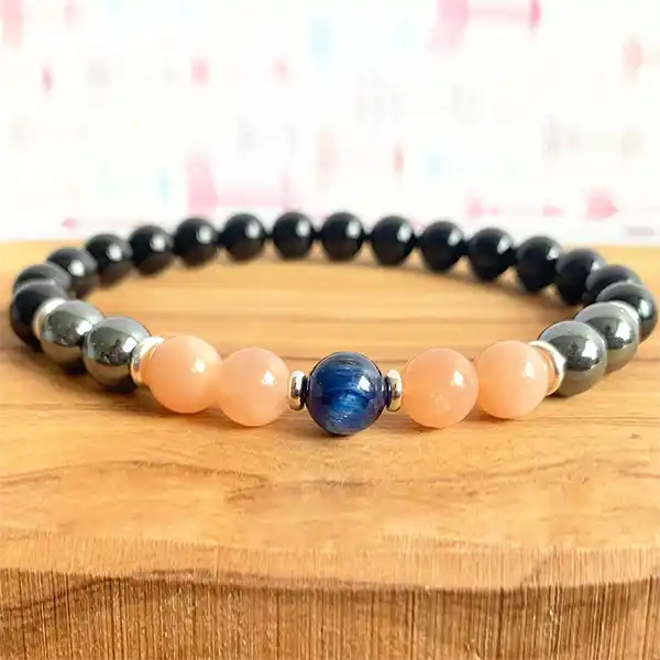 Bracelet Onyx Hématite Pierre de Soleil Cyanite sur un plancher en bois clair kaosix
