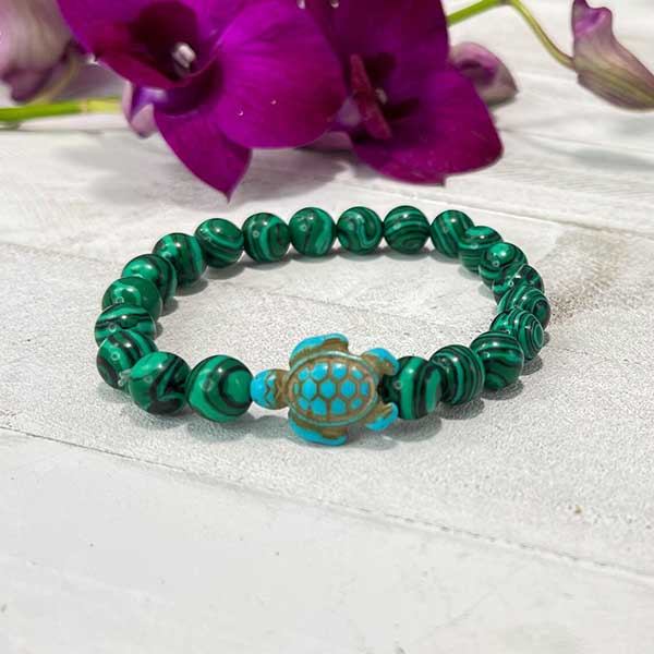 Bracelet Pierre de Malachite Tortue Marine posé sur un parquet en bois blanc Kaosix