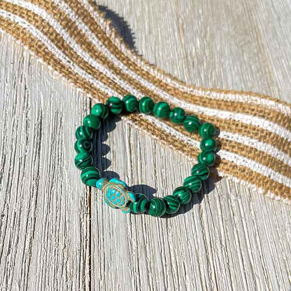 Bracelet Pierre de Malachite Tortue Marine posé sur un parquet en bois gris Kaosix