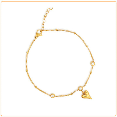 Bracelet de cheville en acier inoxydable doré pendentif cœur et zircons cubiques sur fond blanc Kaosix