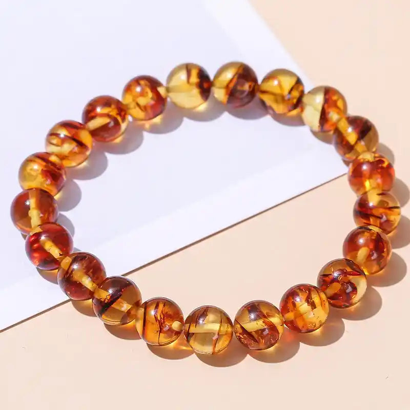 Bracelet en Perles d’Ambre Jaune posé sur une table couleur saumon à cheval sur une feuille blanche Kaosix