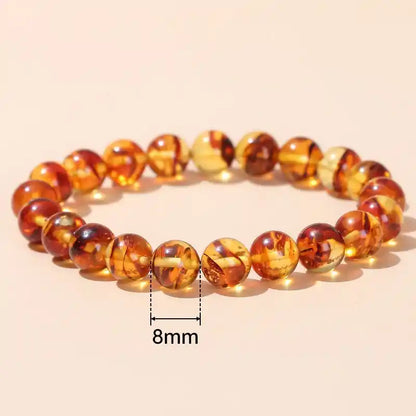Bracelet en Perles d’Ambre Jaune posé sur une table couleur saumon avec la taille d'une perle de 8 mm Kaosix