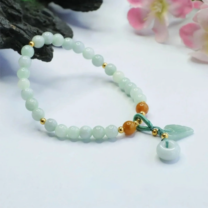 Bracelet en quartz fraise et quartz vert posé sur un rocher gris foncé Kaosix