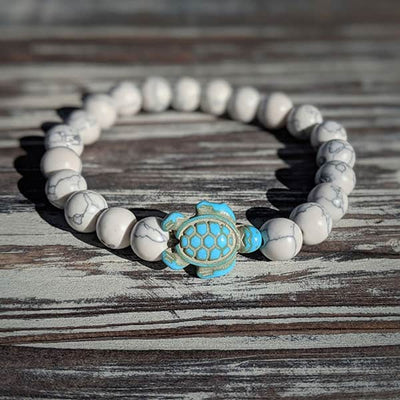 Bracelet howlite blanche Tortue Marine sur une planche en bois gris au soleil Kaosix