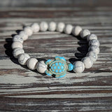 Bracelet howlite blanche Tortue Marine sur une planche en bois gris au soleil Kaosix