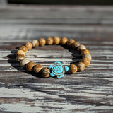 Bracelet jaspe brun Tortue Marine posé sur une planche en bois gris au soleil Kaosix