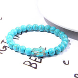 Bracelet pierre bleu turquoise tortue marine posé sur une page blanche avec inscriptions à l'encre noire Kaosix