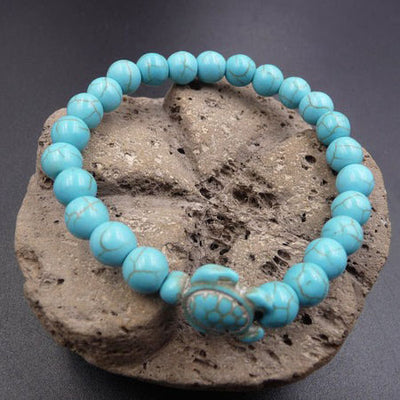 Bracelet pierre bleu turquoise tortue marine sur un rocher posé sur une table grise Kaosix