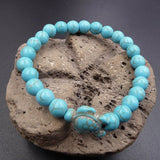 Bracelet pierre bleu turquoise tortue marine sur un rocher posé sur une table grise Kaosix