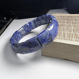 Bracelet pierres plates (plaquettes) Lapis Lazuli posé sur un rebord en bambou sur une table Kaosix