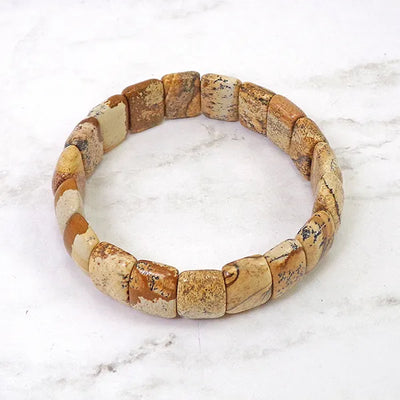 Bracelet pierres plates (plaquettes) jaspe paysage posé sur du marbre gris vue de haut Kaosix
