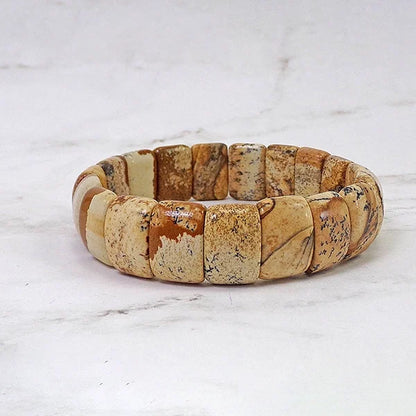 Bracelet pierres plates (plaquettes) jaspe paysage posé sur une table en marbre gris Kaosix