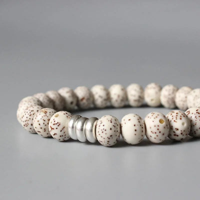 Bracelet tibétain graine de bodhi protection avec gros plan sur les anneaux métalliques et posé sur un sol gris Kaosix