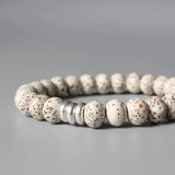 Bracelet tibétain graine de bodhi protection avec gros plan sur les anneaux métalliques et posé sur un sol gris Kaosix