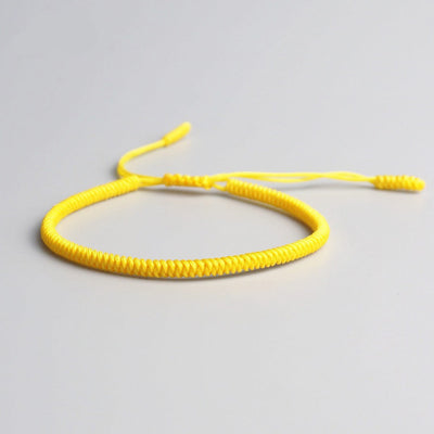 Bracelet tibétain porte-bonheur jaune sur sol gris Kaosix